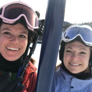 Two women in ski gear on a chair lift.