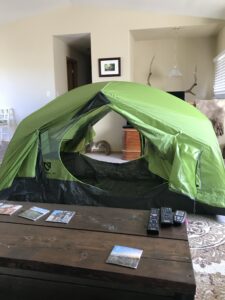 Green tent set up in a living room with doors on both sides open.
