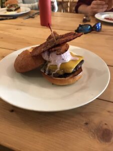 Huckleberries from huckleberry picking can be used to make lot's of delicious food. A cheeseburger on a bun topped with huckleberry ice cream. Yellow cheddar cheese and a toothpick holding it together.