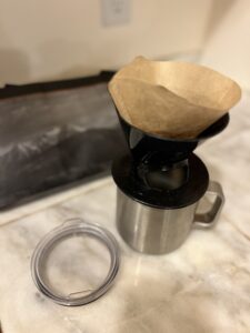 A pour over coffee carafe with a filter in it sitting on a silver Yeti brand coffee mug.